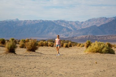 Keşfetmek ve çok sıcak havalarda Ölüm Vadisi çölün ortasında büyük kumulları aşağı yürüyüş güzel kız.