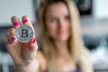 Bir bitcoin para elinde tutan genç kız.