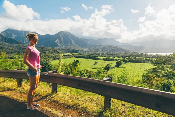 Beautiful sexy lady standing on the top of the peak with an amazing view on Kauai island in Hawaii watching landscape, mountains and green nature. Successful life. Living your life.