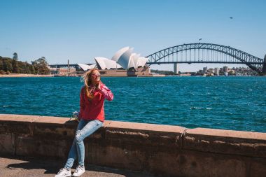 Genç Kız parkta Sydney Opera Binası ve Harbour Köprüsü tarafından yürüyüş. Sydney. Avustralya. 30 Ağustos 2017.