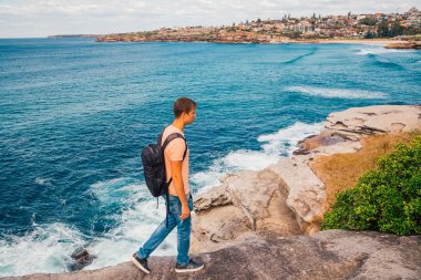 Genç adam Bondi beach kayalıklardan yakınındaki Sydney Avustralya'da keşfetmek. Doğa hiking.