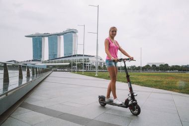 20 Mayıs 2017. Singapur. Şehrin üzerinde şaşırtıcı bir görünümü ile Singapur elektrikli bir scooter sürme genç sevimli kız.