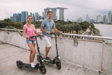 10 Nisan 2017. Singapur. Genç çift şaşırtıcı bir görünümü ile Singapur elektrikli bir scooter sürme.