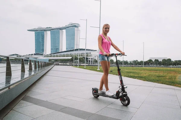 20 Mayıs 2017. Singapur. Şehrin üzerinde şaşırtıcı bir görünümü ile Singapur elektrikli bir scooter sürme genç sevimli kız.