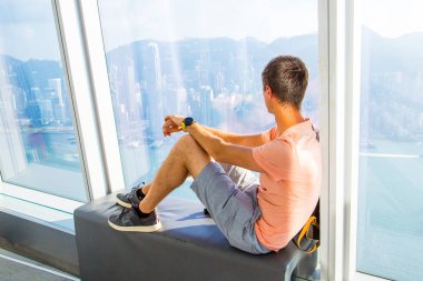 30 Ağustos 2017. Hong Kong. Çin. Genç adam Hong Kong gökdelen penceresinde kenarında otururken yukarıdan şehir izlerken.