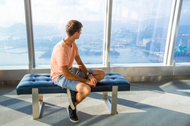 30 Ağustos 2017. Hong Kong. Çin. Genç adam Hong Kong gökdelen penceresinde kenarında otururken yukarıdan şehir izlerken.