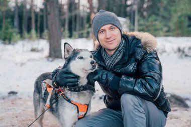Genç adam tarafından kızakları husky köpek kış ormandaki oynamaktan.