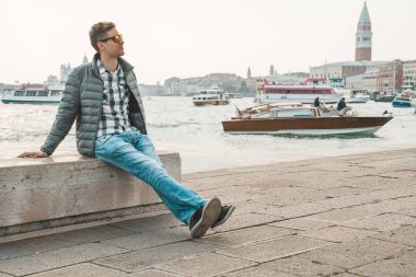 Venedik, İtalya. 10 Nisan 2018. Venedik keşfetmek bir genç adam. Rialto Köprüsü yanı sıra San Marco Meydanı geçirerek gondol izlerken Kanallar başına oturmuş.