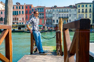Venedik, İtalya. 10 Nisan 2018. Venedik keşfetmek bir genç adam. Rialto Köprüsü yanı sıra San Marco Meydanı geçirerek gondol izlerken Kanallar başına oturmuş. 