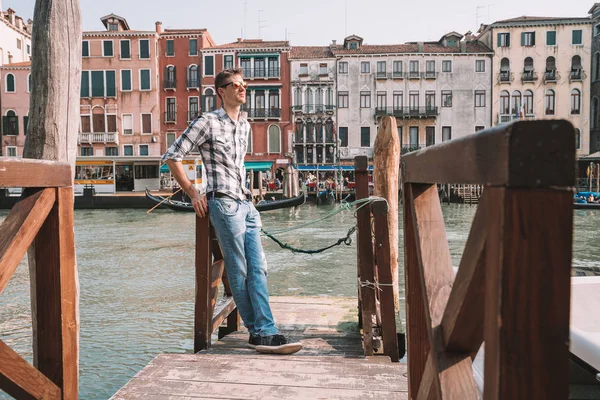 Venedik, İtalya. 10 Nisan 2018. Venedik keşfetmek bir genç adam. Rialto Köprüsü yanı sıra San Marco Meydanı geçirerek gondol izlerken Kanallar başına oturmuş.