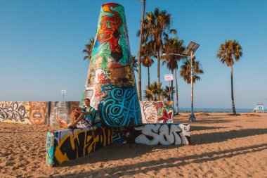 Los Angeles'taki Venedik Plajı'nda oturan genç adam.