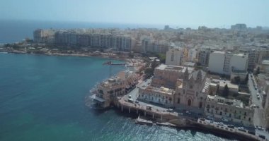 Geleneksel Malta Luzzu balıkçı tekneleri ve güzel manzaralı St Julian, Sliema ve Valetta şehirler yukarıdan Spinola Bay üzerinde havadan görünümü.
