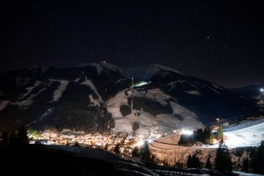 Alpler 'de güzel bir gece. Gökyüzü yıldızlarla dolu dağların arasında küçük bir kayak köyü..