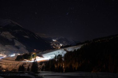 Alpler 'de güzel bir gece. Gökyüzü yıldızlarla dolu dağların arasında küçük bir kayak köyü..