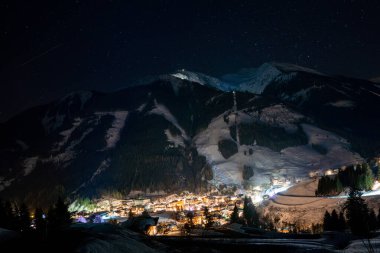 Alpler 'de güzel bir gece. Gökyüzü yıldızlarla dolu dağların arasında küçük bir kayak köyü..