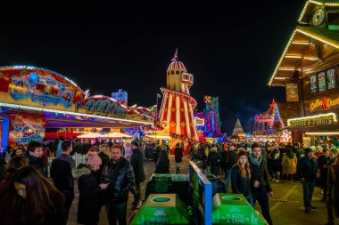 London, UK. December 2, 2019. London Wonderland. Night view of people walking in the Hyde Park's winter Wonder Land between different rides and attractions. Beautiful Christmas spirit in London.
