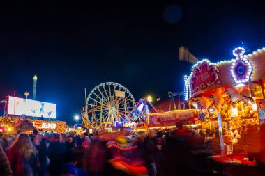 London, UK. December 2, 2019. London Wonderland. Night view of people walking in the Hyde Park's winter Wonder Land between different rides and attractions. Beautiful Christmas spirit in London.
