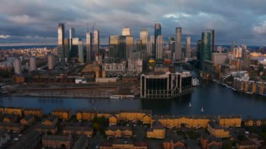 Aerial Panoramic skyline view of Bank and Canary Wharf, central London's leading financial districts with famous skyscrapers at golden hour sunset during cloudy skies. London, England