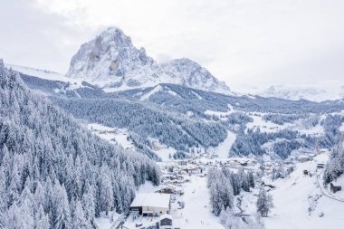 Slope on the Alpine skiing resort Val Gardena in Italy. Mighty mountains and forest covered in snow.