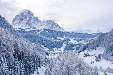 Slope on the Alpine skiing resort Val Gardena in Italy. Mighty mountains and forest covered in snow.
