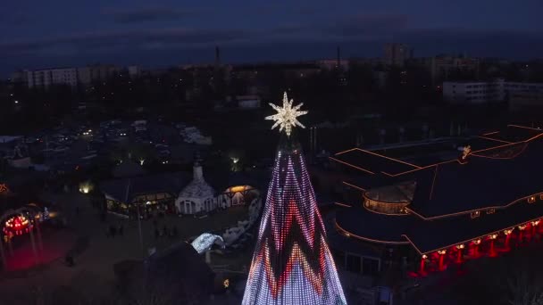 ラトビアのリガに位置するヨーロッパで最も美しいクリスマスツリーは リドのレストラン施設で クリスマスツリーの美しい夜景とクリスマスアイススケートを祝う人々 — ストック動画