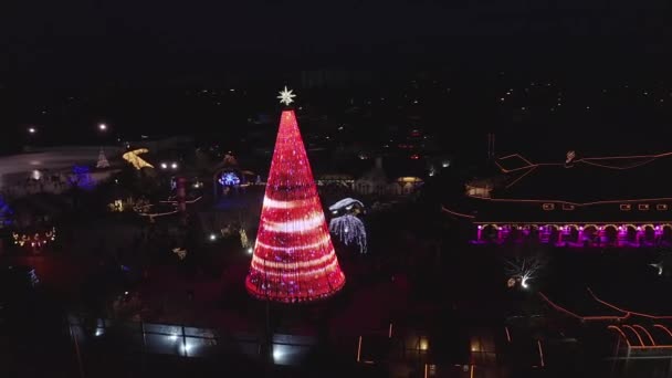 ラトビアのリガに位置するヨーロッパで最も美しいクリスマスツリーは リドのレストラン施設で クリスマスツリーの美しい夜景とクリスマスアイススケートを祝う人々 — ストック動画