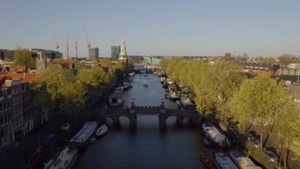 荷兰阿姆斯特丹 无人驾驶飞机俯瞰威斯特克尔克教堂和有桥梁和船只的狭窄运河 — 图库视频影像