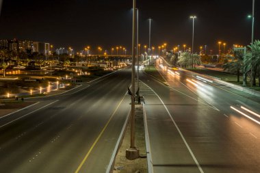 Abu Dabi 'nin gece caddelerinde hızla ilerleyen trafiğin gece görüşü. Günbatımında kalabalık Abu Dabi şehrinde araba hareketi.
