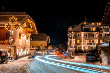 Val Garden, İtalya. 24 Aralık 2019. İtalyan Alpleri 'ndeki karla kaplı kulübelerin gece manzarası. Noel zamanı, süslü Noel ağaçları ve ahşap evlerle dolu rahat gece sokakları.