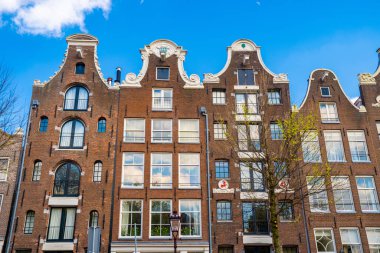 Amsterdam, Hollanda. 20 Mayıs 2019. Açık yaz gökyüzü boyunca kanallar ve tipik geleneksel evler. Hollanda 'da klasik mimari. 