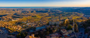 Monte Titano 'daki Guaita kalesinin hava manzaralı güzel manzarası ve arka planda San Marino şehri gün doğumunda. San Marino 'nun güzel tarihi merkezi. Tepenin tepesinde bir kale.