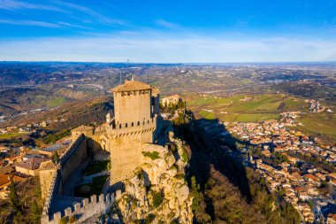 Monte Titano 'daki Guaita kalesinin hava manzaralı güzel manzarası ve arka planda San Marino şehri gün doğumunda. San Marino 'nun güzel tarihi merkezi. Tepenin tepesinde bir kale.