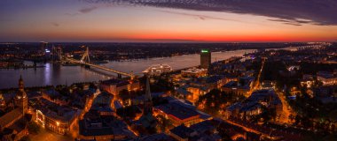 Büyülü pembe günbatımında Riga 'nın eski kasabasının güzel panoramik manzarası. Şehir sokak lambalarıyla aydınlanıyor..