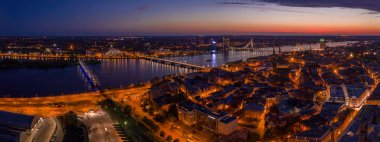 Büyülü pembe günbatımında Riga 'nın eski kasabasının güzel panoramik manzarası. Şehir sokak lambalarıyla aydınlanıyor..