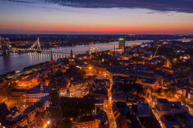 Büyülü pembe günbatımında Riga 'nın eski kasabasının güzel panoramik manzarası. Şehir sokak lambalarıyla aydınlanıyor..