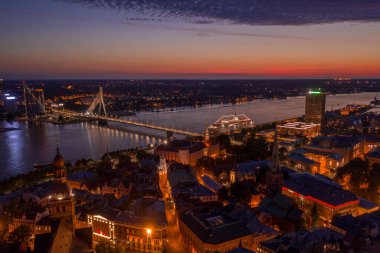 Büyülü pembe günbatımında Riga 'nın eski kasabasının güzel panoramik manzarası. Şehir sokak lambalarıyla aydınlanıyor..