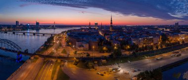 Büyülü pembe günbatımında Riga 'nın eski kasabasının güzel panoramik manzarası. Şehir sokak lambalarıyla aydınlanıyor..