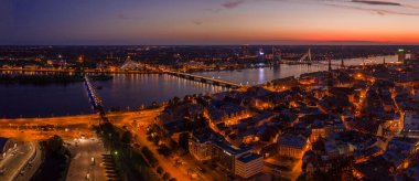 Büyülü pembe günbatımında Riga 'nın eski kasabasının güzel panoramik manzarası. Şehir sokak lambalarıyla aydınlanıyor..