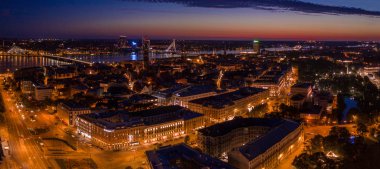Büyülü pembe günbatımında Riga 'nın eski kasabasının güzel panoramik manzarası. Şehir sokak lambalarıyla aydınlanıyor..