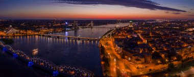 Büyülü pembe günbatımında Riga 'nın eski kasabasının güzel panoramik manzarası. Şehir sokak lambalarıyla aydınlanıyor..