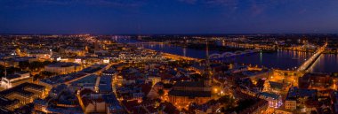 Büyülü pembe günbatımında Riga 'nın eski kasabasının güzel panoramik manzarası. Şehir sokak lambalarıyla aydınlanıyor..