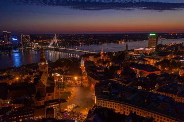 Büyülü pembe günbatımında Riga 'nın eski kasabasının güzel panoramik manzarası. Şehir sokak lambalarıyla aydınlanıyor..