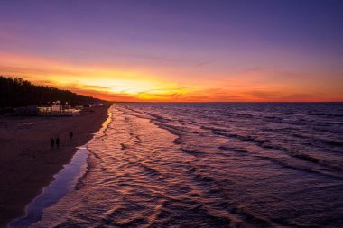 Letonya 'nın Jurmala şehrinde destansı mor gün batımı. Baltık Denizi kıyısında büyülü sahil günbatımı. Hava görünümü.