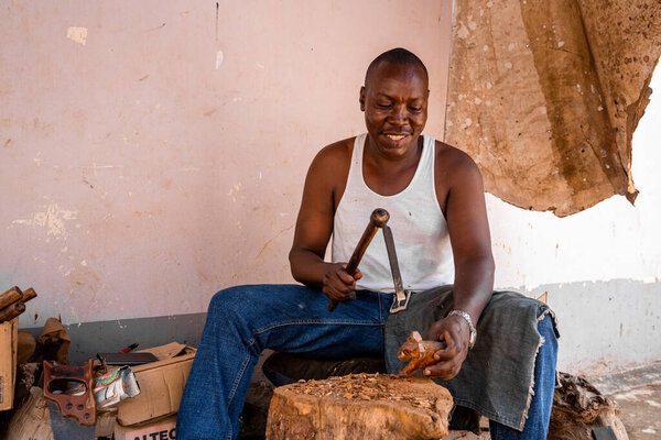 Tanzania, Kilimanjaro. March 20, 2020. Concept of diy. Man is making a wooden animal figure to sell as a souvenir.