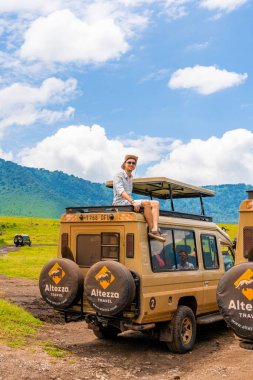 Ngorongoro Krateri, Tanzanya, Afrika - 5 Mart 2020. Genç adam cipin tepesinde oturmuş Ngorongoro Ulusal Parkı 'nı keşfediyor. Safari kaşifi kavramı.