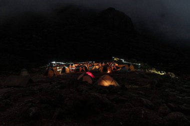 Kilimajaro Dağı 'nın üzerinde yıldızlar. Panoramik, en yüksek Afrika dağının gece manzarası, dolunay ile aydınlanan yıldızlı mavi gökyüzü. Savanna görünümü