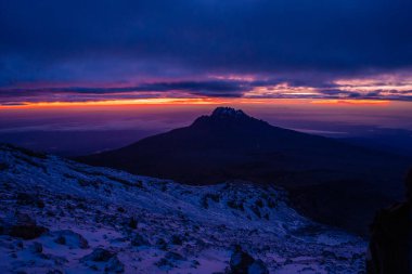 Uhuru Tepesi 'nde gün doğumu, Mt. Kilimanjaro, ön planda kayalarla destansı Mor Dağ Gündoğumu.