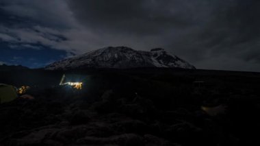 Kilimanjaro Dağı 'nın eteklerinde kamp kuran çadırlar. Çadırların üzerinde hareket eden bulutların güzel zaman çizelgesi. 