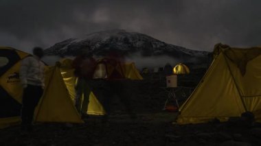 Kilimanjaro Dağı 'nın eteklerinde kamp kuran çadırlar. Çadırların üzerinde hareket eden bulutların güzel zaman çizelgesi. 