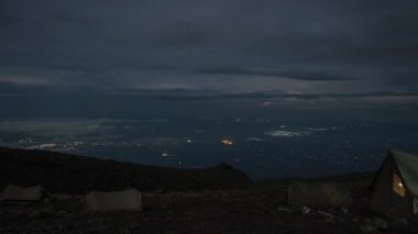 Kilimanjaro Dağı 'nın eteklerinde kamp kuran çadırlar. Çadırların üzerinde hareket eden bulutların güzel zaman çizelgesi. 